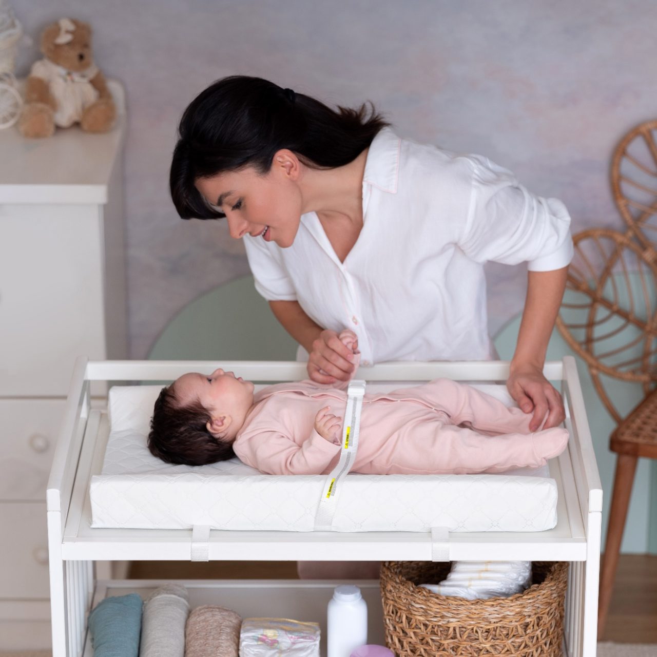 Mother changing her baby on a baby'ness quilted changing mat on a changing table